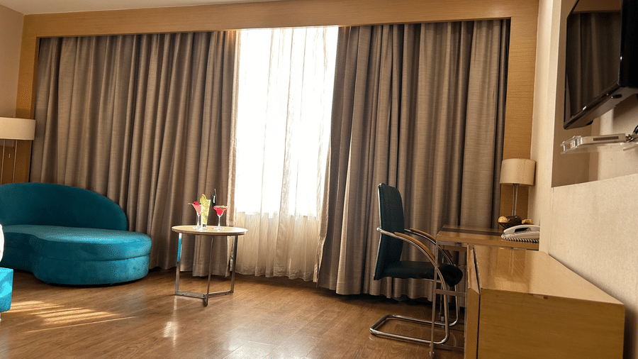 Seating area with round table, chairs and floor-to-ceiling window inside the room at The Conway, Meerut