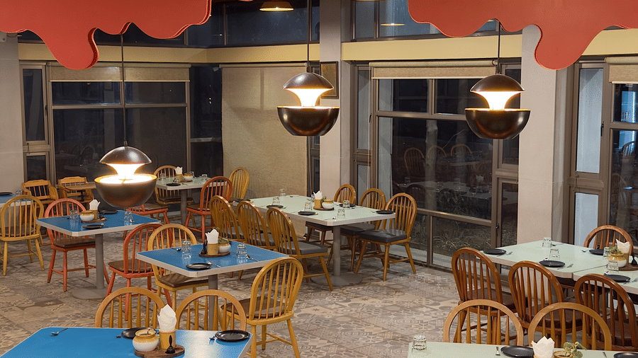 The restaurant at Vinti Resort, Ambaji, warmly lit for dinner, features a striking ceiling and comfortable tables set for dining.