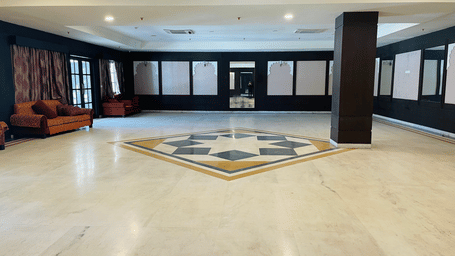 A spacious Raj Samelan hall at Shri Vallabh Villas Lords Plaza Nathdwara with tiled floors, dark columns, and minimal furnishings.