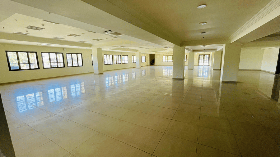 A naturally well-lit indoor view of Raj Darbar Hall featuring pillars and series of windows.