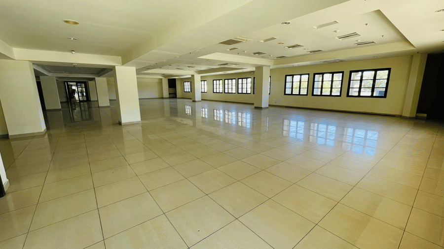 An empty interior view of Raj Darbar Hall with pillars and multiple windows.