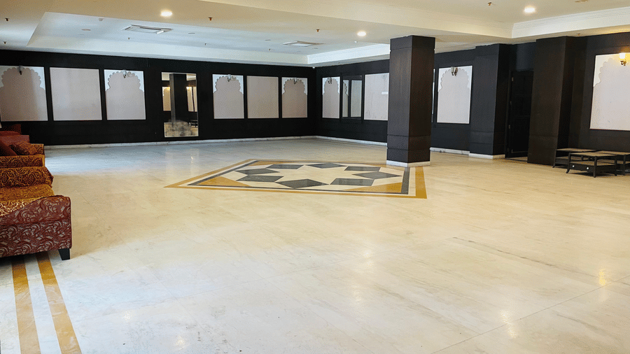 An interior view of Raj Samelan Hall at Shri Vallabh Villas Lords Plaza Nathdwara with a pillar and arranged sofas.