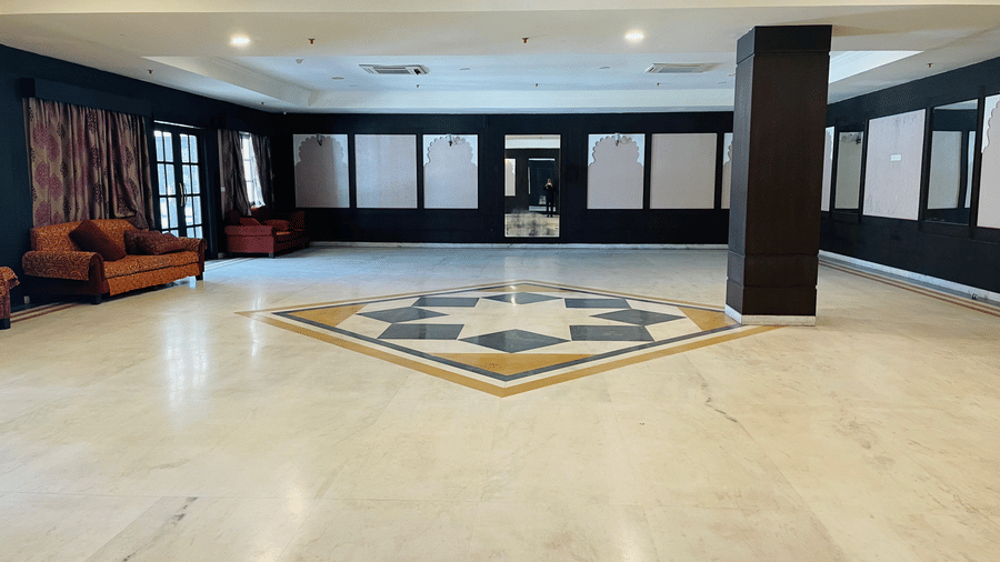 A spacious Raj Samelan hall at Shri Vallabh Villas Lords Plaza Nathdwara with tiled floors, dark columns, and minimal furnishings.