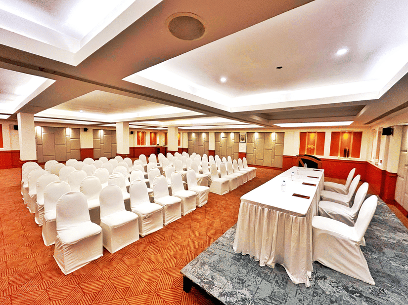 Banquet hall set up in theatre-style seating with white chairs and a head table at The Residency Karur, ideal for conferences and formal gatherings