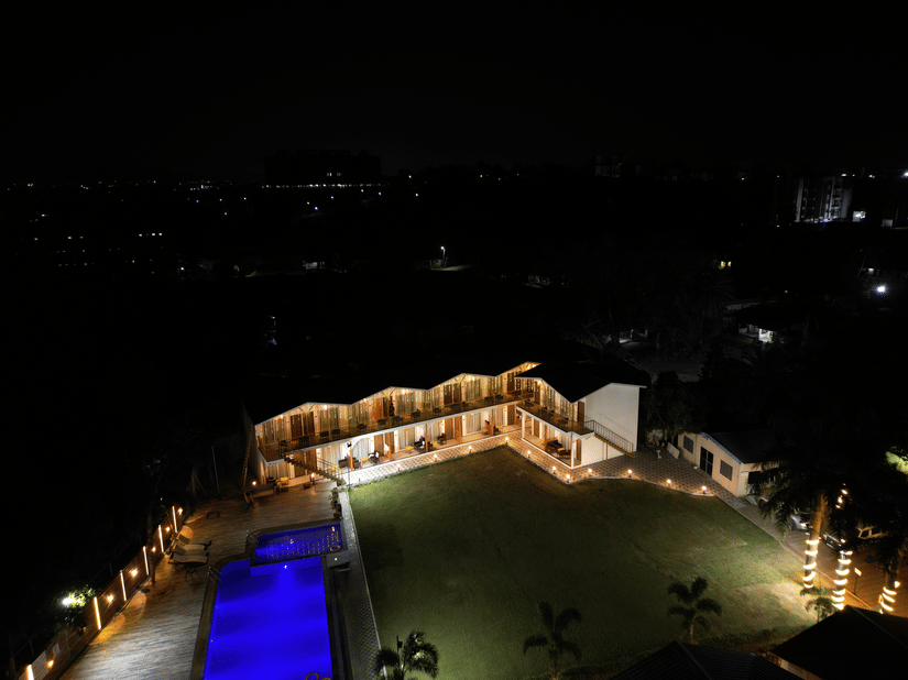 Aerial night view of VITS Daman Devka Beach illuminated against the dark skyline with the swimming pool visible in the foreground.
