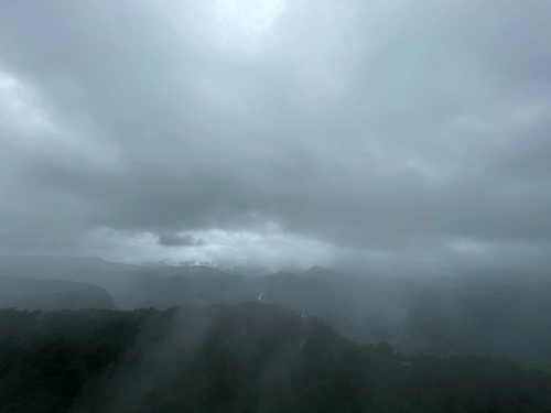 A view of Anamalai HIlls in the Western Ghats with mist covering the entire area and dark clouds above.
