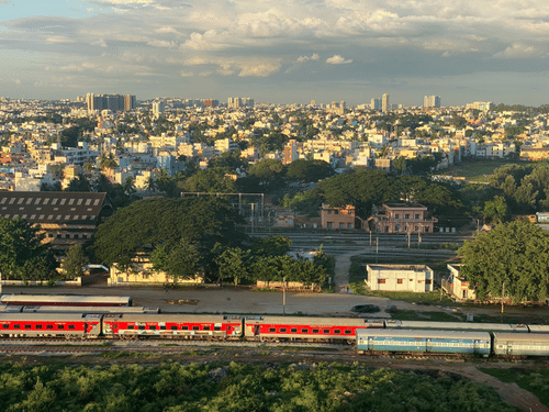 A wide shot of a train travelling through the landscape with a city skyline in the background.