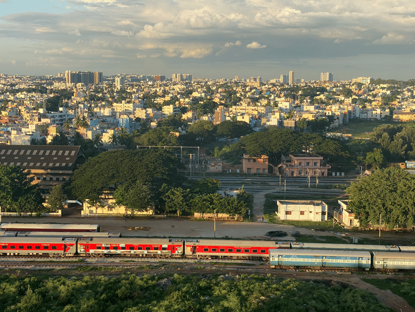 A wide shot of a train travelling through the landscape with a city skyline in the background.