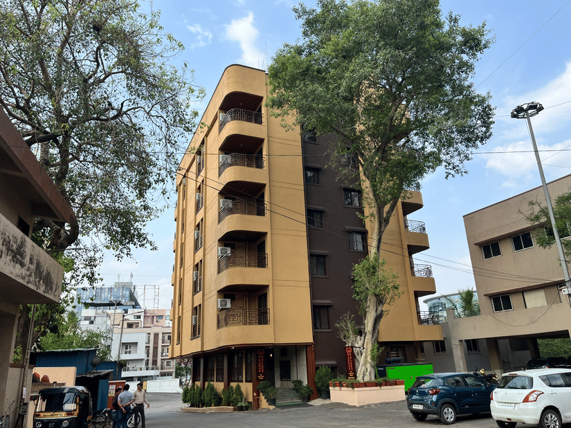 Another angle of the facade image of a building with a large tree in front at VITS Select Kharadi, Pune.