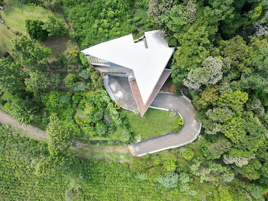 Aerial view of a modern hillside villa surrounded by dense green forest at Ibex Resorts, Coonoor (Tapas).