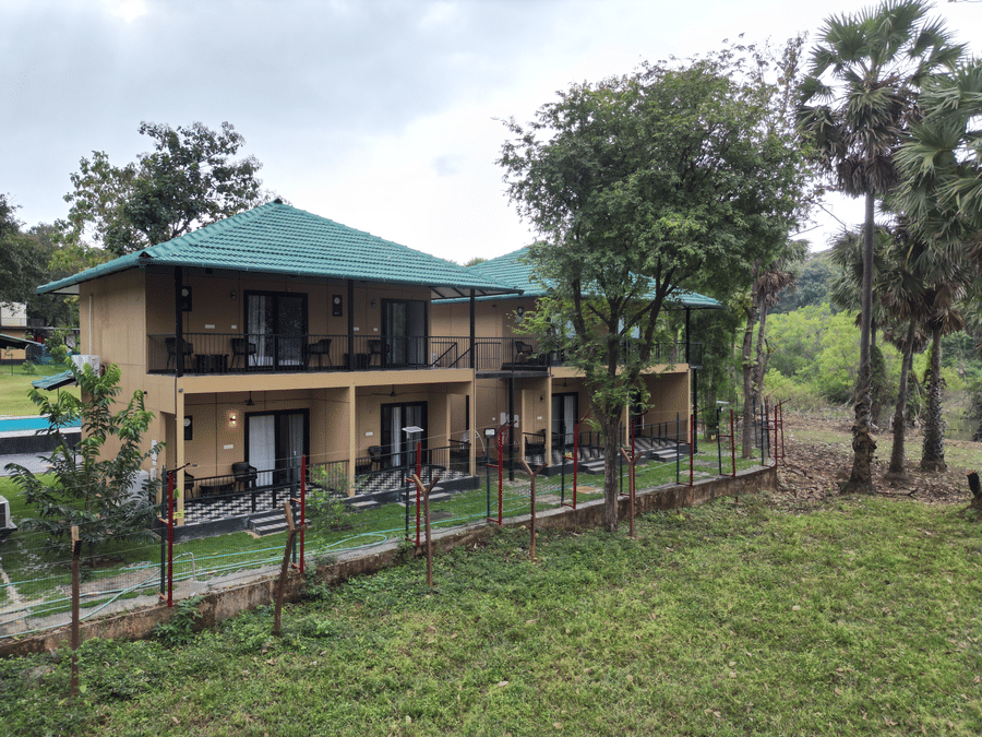 2-storey resort building with private balconies surrounded by a lush natural landscape and tall trees - Ibex Resorts, Malampuzha (Kava Eco Camp and Caravan Park)