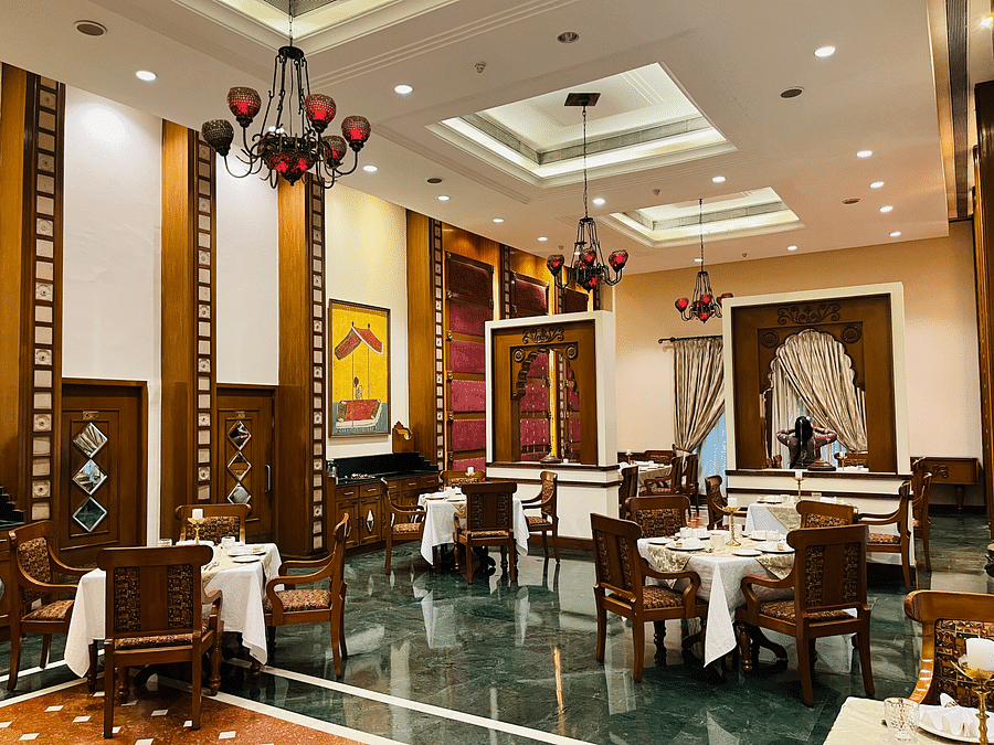 Corner view of the Kesar Royal Seating area, featuring exquisite wooden furnishings and a regal aesthetic at Kesar Restaurant, The Ummed Ahmedabad.