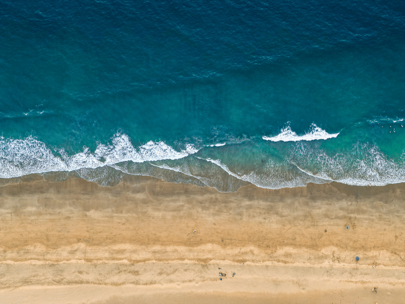 A top-down aerial view of Agonda Beach with the blue0green waves crashing on the shoreline.