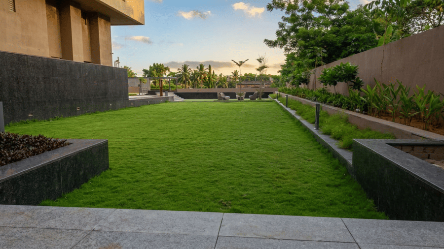 A well-manicured lawn at Prachi Sarovar Premiere, Bhubaneswar, situated beside the hotel building, with a partially cloudy sky seen in the background.