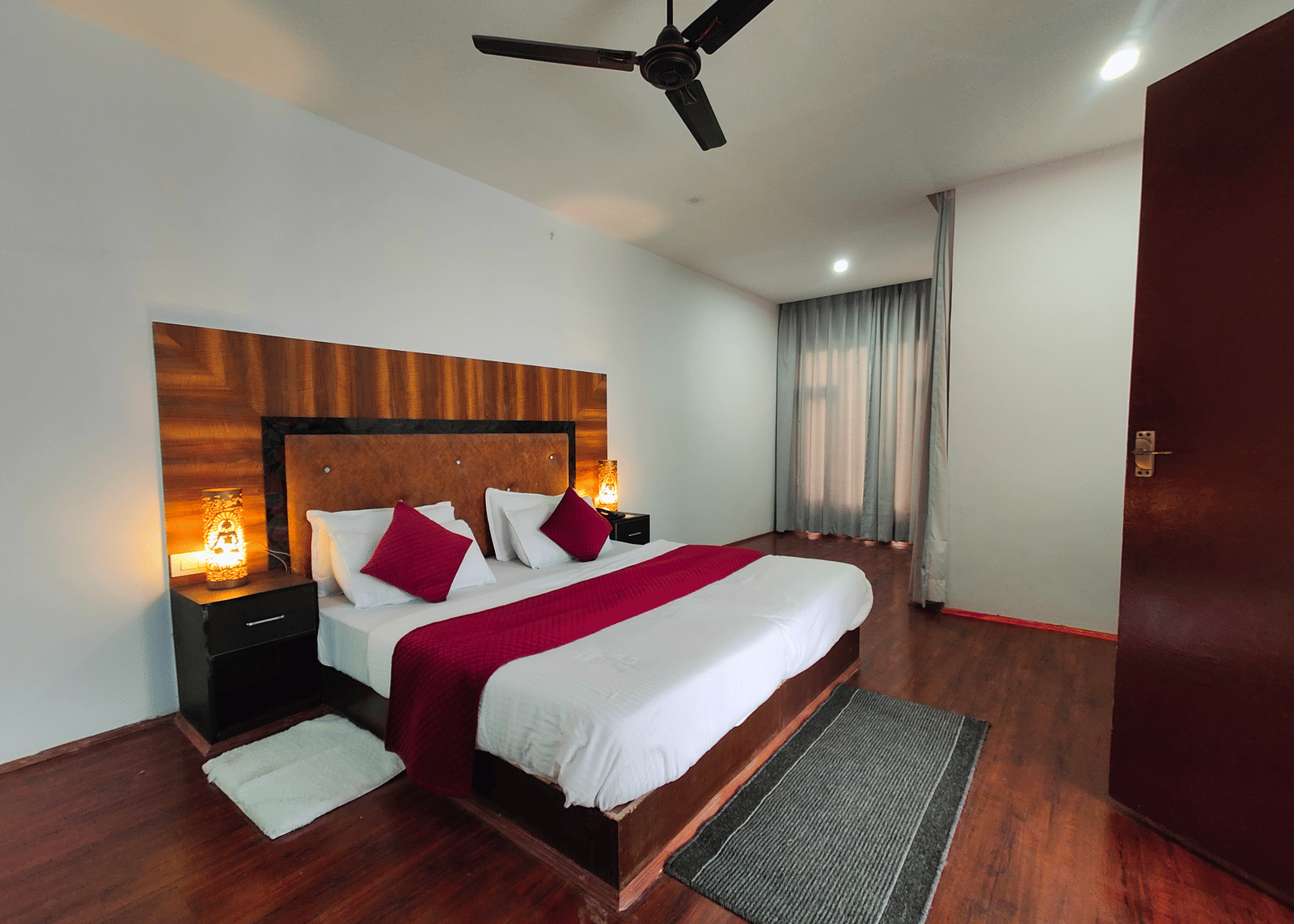 A wide-angle view of a bedroom featuring warm ambient lighting from bedside lamps at Indus Serenity Retreat.