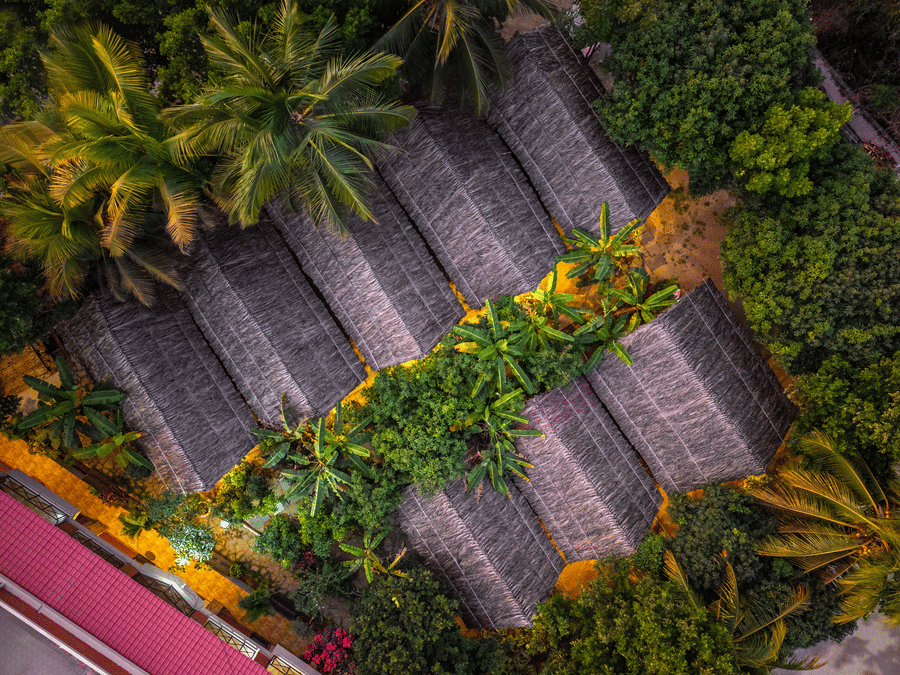 Bird's-eye view of the resort's thatched roof cottages nestled among lush green trees - Nature Trails Ashoka Resort Hampi