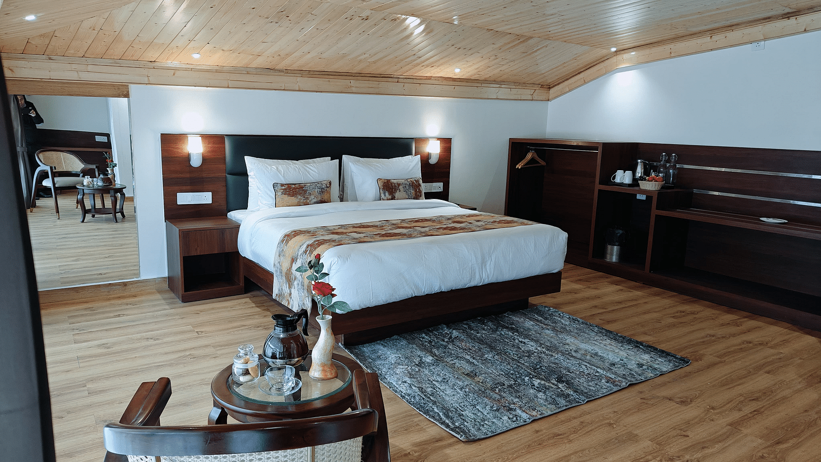 A hotel room in Darjeeling with a neatly made bed, side tables, and a patterned rug, offering a cosy and inviting feel - Sumitel JB Park, Darjeeling