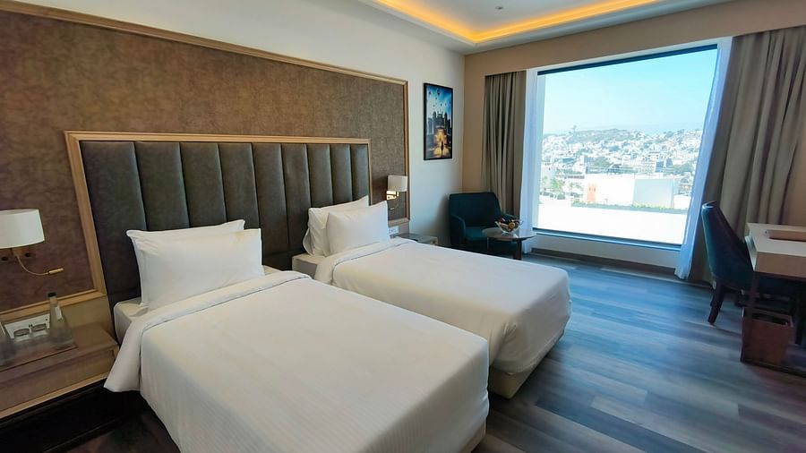 A hotel room in Ajmer with a twin bed setup, stylish furniture, and ample natural light - Sarovar Portico, Ajmer