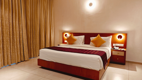 A well-appointed deluxe room at Bliss Giriya By Bergamont Tiruvannamalai with a double bed and warm wall lighting.