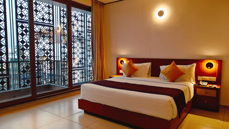 A heritage-styled room at Bliss Giriya By Bergamont Tiruvannamalai with a double bed, carved wooden screen windows, and warm wall lighting.