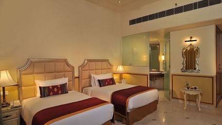 Image of a room with two beds and lamps on the sides of the bed at Rajasthali Resort & Spa Jaipur.