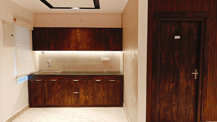 A wooden kitchenette with a dark countertop and 1 sink is located next to a matching wooden door at Bliss Casa Mila By Bergamont Hotels, Kodaikanal.