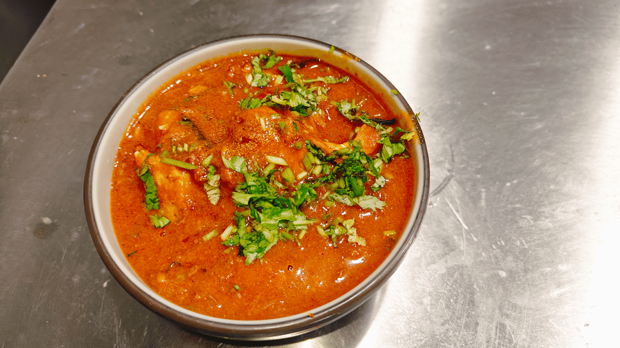 A bowl of thick orange-coloured meat curry topped with freshly chopped coriander leaves at Bliss Casa Mila By Bergamont Hotels, Kodaikanal.