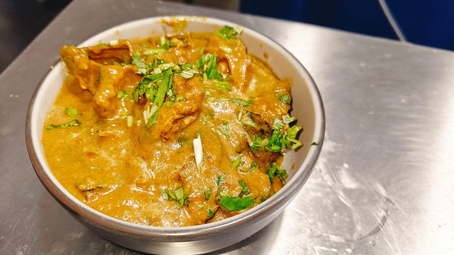 A bowl containing meat pieces in a thick, light-brown gravy garnished with green coriander at Bliss Casa Mila By Bergamont Hotels, Kodaikanal.
