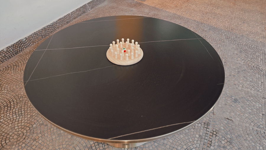 A large round black table features a small circular wooden game board with white pegs in the centre at Bliss Casa Mila By Bergamont Hotels, Kodaikanal.