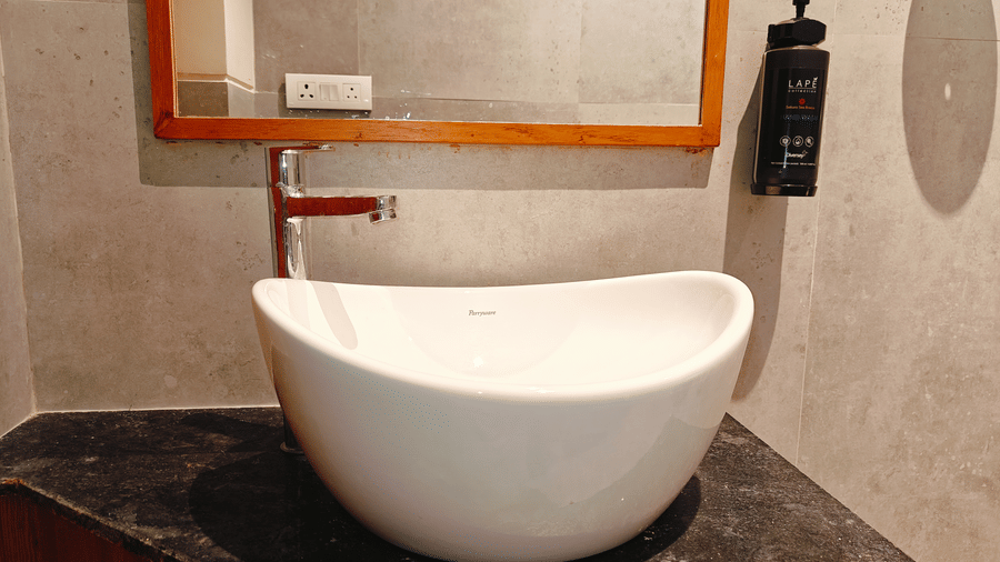 A modern bathroom at Bliss Giriya By Bergamont Tiruvannamalai with a freestanding oval bathtub and stone-clad flooring.