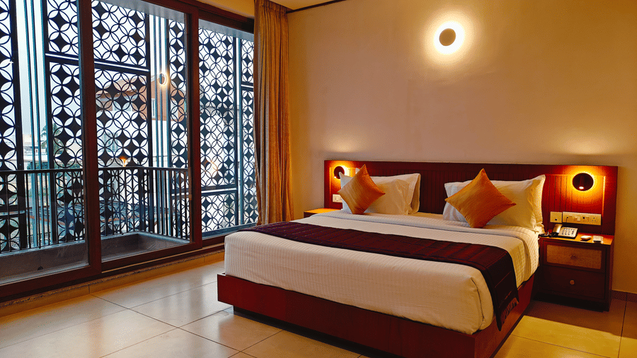 A heritage-styled room at Bliss Giriya By Bergamont Tiruvannamalai with a double bed, carved wooden screen windows, and warm wall lighting.