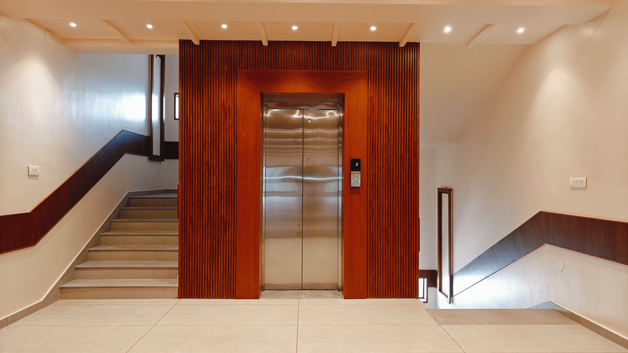 A lift lobby at Bliss Giriya By Bergamont Tiruvannamalai with wooden lift doors and an adjoining staircase.