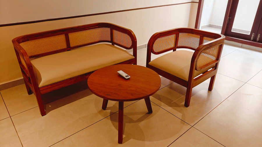 A sitting area at Bliss Giriya By Bergamont Tiruvannamalai with a wooden sofa set and round coffee table.