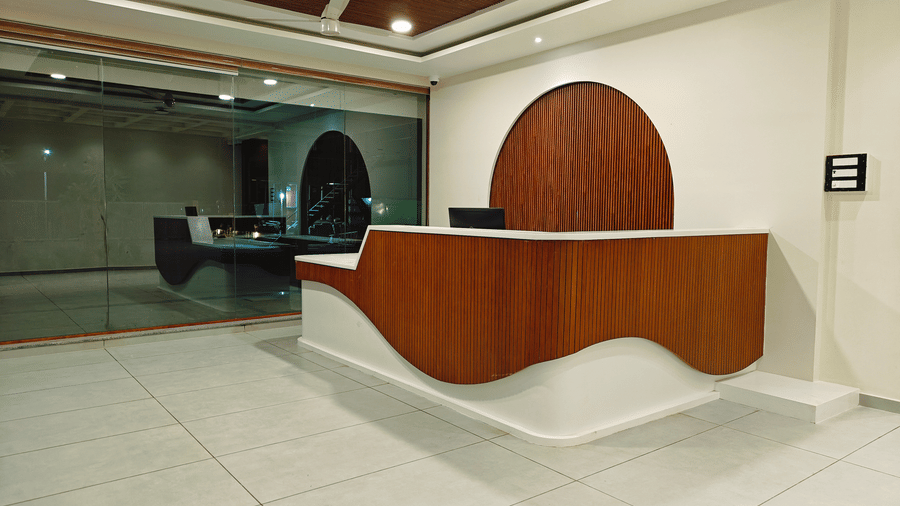 A side view of the curved wooden reception desk at the lobby of Bliss Giriya By Bergamont Tiruvannamalai.