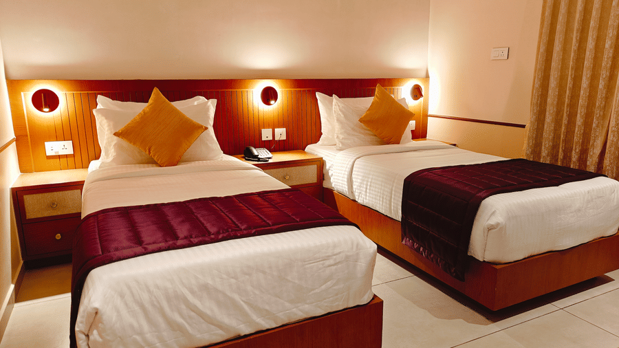 A neatly made bed with a wooden headboard and wall-mounted reading lights at Bliss Giriya By Bergamont Tiruvannamalai.