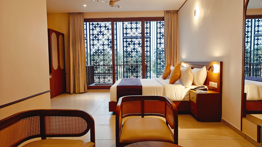 A well-appointed room at Bliss Giriya By Bergamont Tiruvannamalai with a double bed, wooden chairs, and louvred windows.