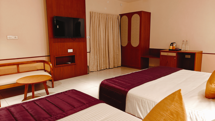 A hotel room at Bliss Giriya By Bergamont Tiruvannamalai with a double bed, wall-mounted television, and a wooden wardrobe unit.