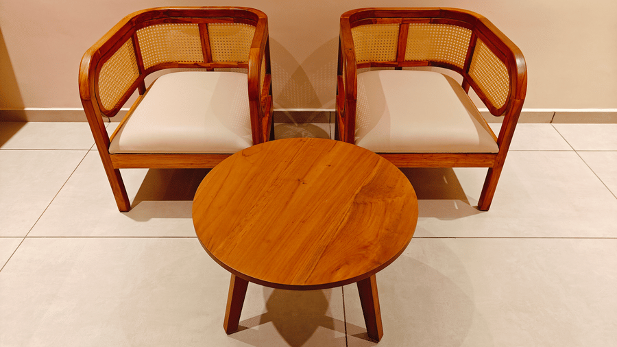 A compact seating area at Bliss Giriya By Bergamont Tiruvannamalai with two wooden chairs and a round side table.