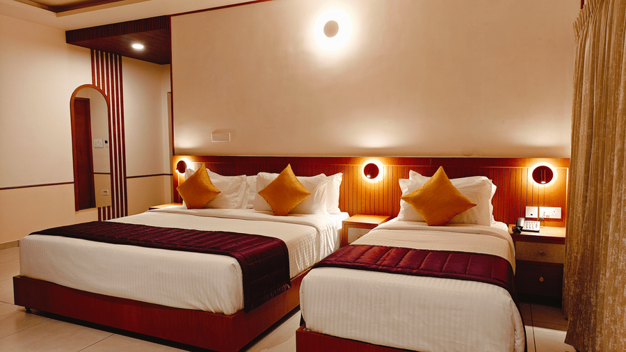 A twin-bedded room at Bliss Giriya By Bergamont Tiruvannamalai with wooden headboards and wall-mounted reading lights.