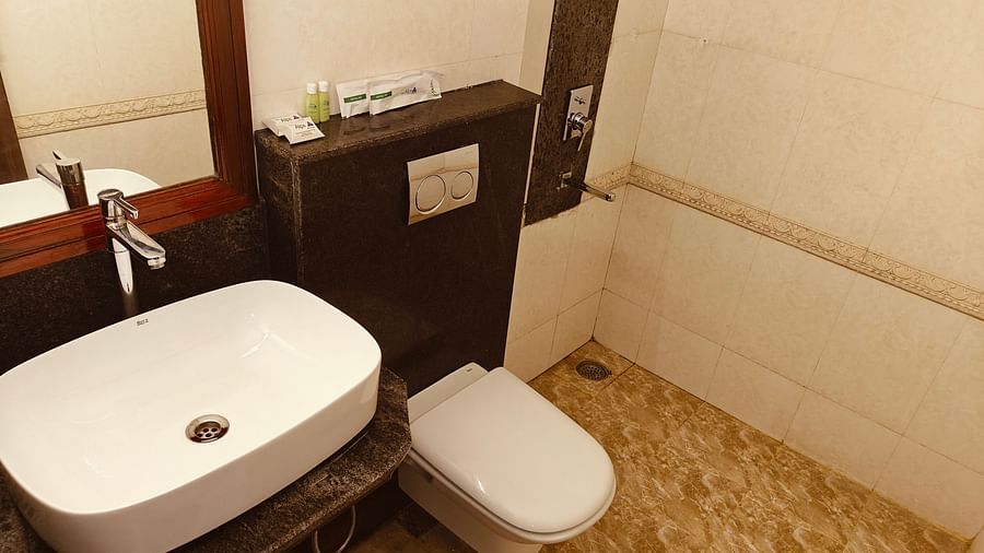 Modern bathroom with sleek sink and western toilet at Hotel Alps Residency, Krishnagiri.
