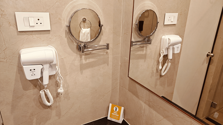 MM Legacy, Kanchipuram | A bathroom with a toilet seat, towels, and other toileteries.