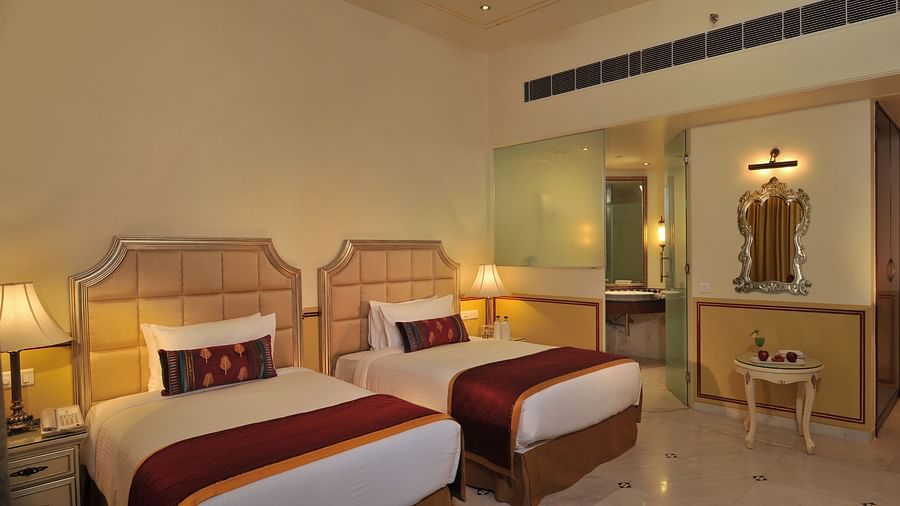 Image of a room with two beds and lamps on the sides of the bed at Rajasthali Resort & Spa Jaipur.