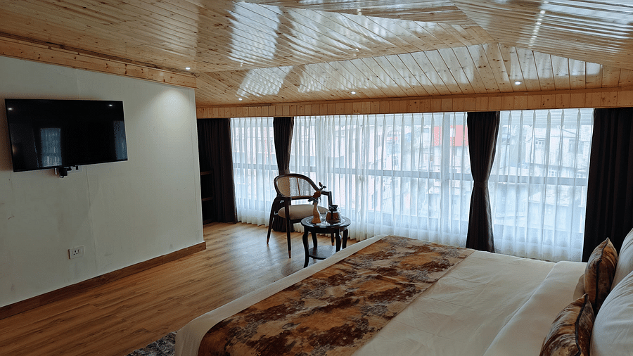 A hotel room with a tv mounted on the wall, a chair, and a decorative runner on the bed - Sumitel JB Park, hotel in Darjeeling