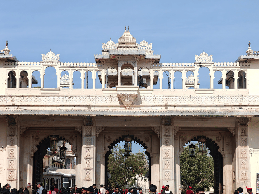 Arched entrance gate of Udaipur City Palace with visitors below.