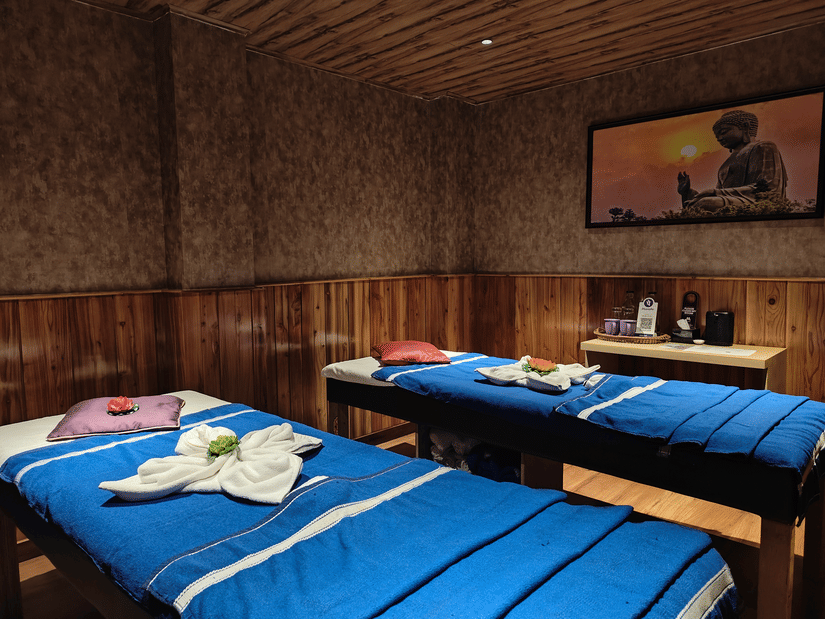 A spa room with twin massage beds, warm wooden interiors, soft lighting, and neatly arranged towels creating a calming wellness experience | Mount Lungta Boutique Hotel & Spa