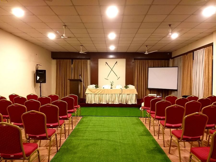 A conference room with rows of red chairs, a podium, and a projection screen.