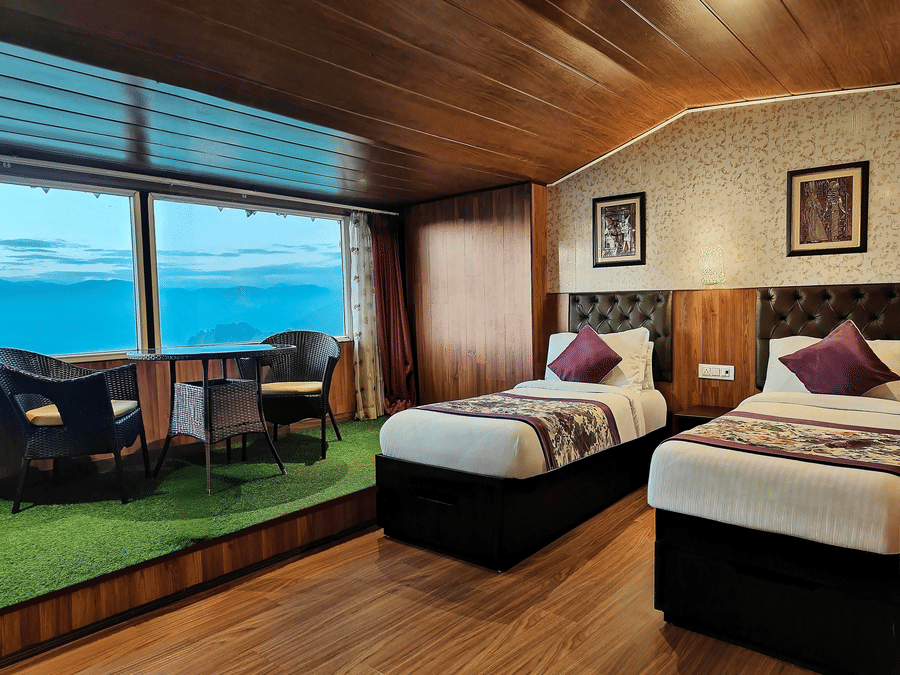 Twin bed room with large glass windows overlooking scenic hills at Mount Thistle Boutique Hotel, Darjeeling.