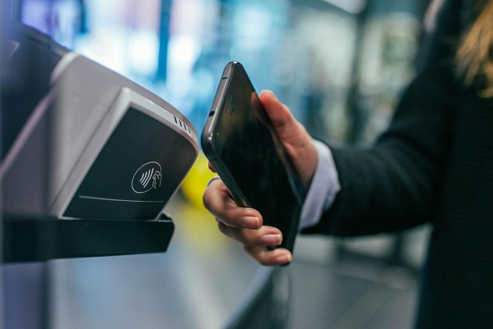A close up of a person using his phone to make a payment at a shop with the background blurred.