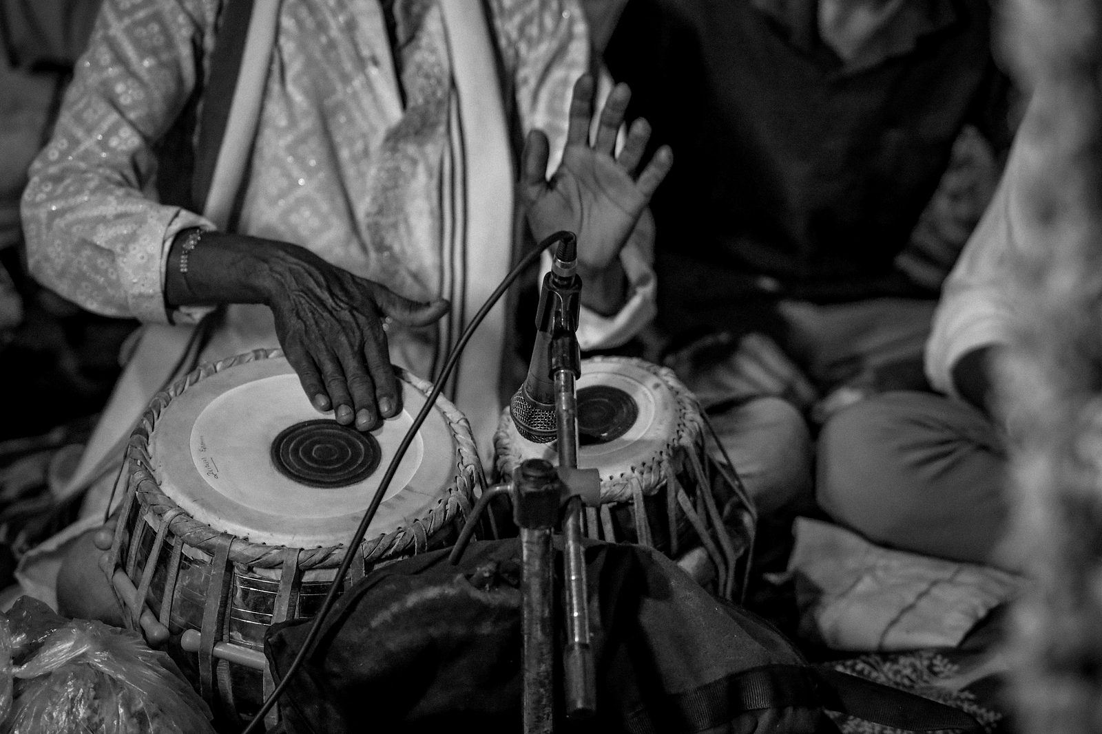 image of a person playing tabla with a mic to amplify the percussion of the instrument