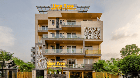 Multiple storey facade of Lime Tree Hotel Near Medanta-The Medicity, Gurgaon featuring an entrance with lawn leading to a building with balconies in each floor attached to the rooms